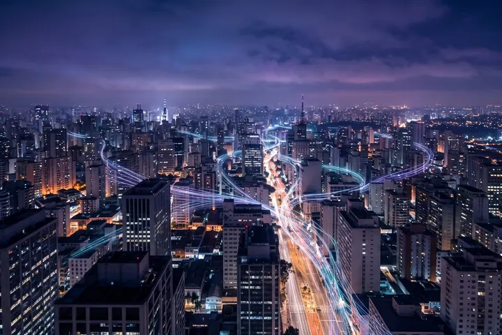 São Paulo à noite vista do alto, com feixes de luz entre os arranha-céus