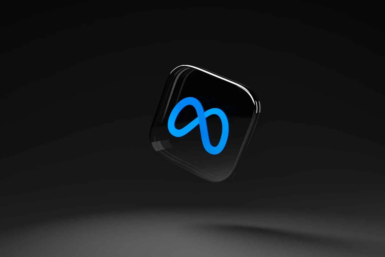 Logotipo azul da Meta, um laço infinito luminoso, sobre um ícone preto de cantos arredondados flutuando em um fundo escuro
