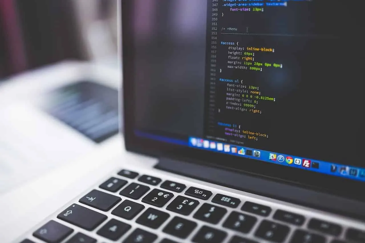 Notebook com código de programação na tela e um teclado em primeiro plano, com o fundo desfocado