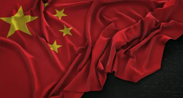 Bandeira da China com uma estrela amarela grande e quatro menores, amarrotada sobre um fundo escuro