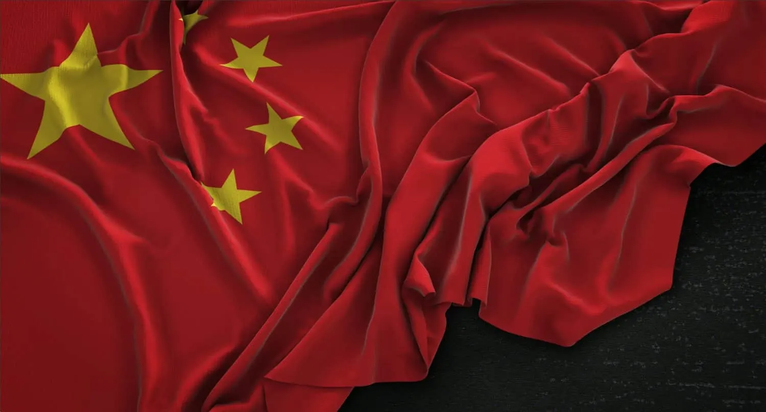 Bandeira da China com uma estrela amarela grande e quatro menores, amarrotada sobre um fundo escuro