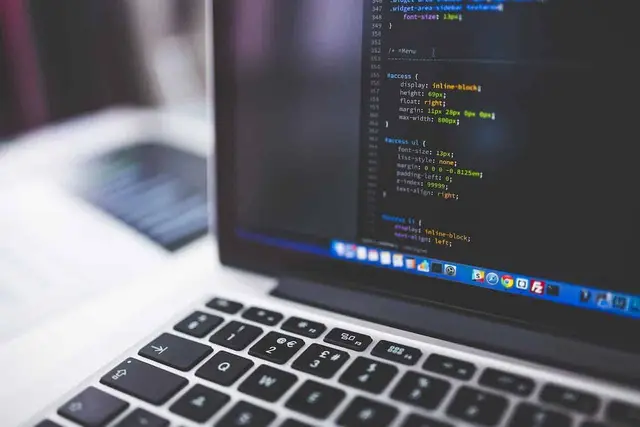 Notebook com código de programação na tela e um teclado em primeiro plano, com o fundo desfocado
