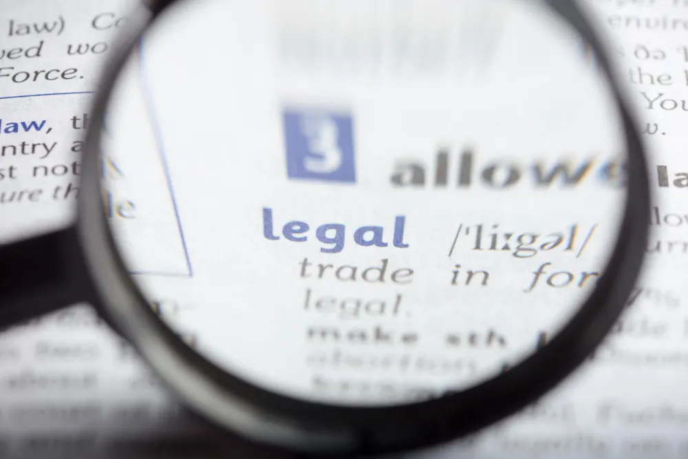 Lupa que amplia a palavra «legal» em um verbete de dicionário, com letras azuis e cinzas desfocadas ao redor.