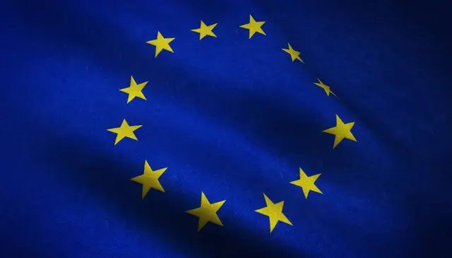 Bandeira da União Europeia ondulando, com doze estrelas amarelas em círculo sobre fundo azul.
