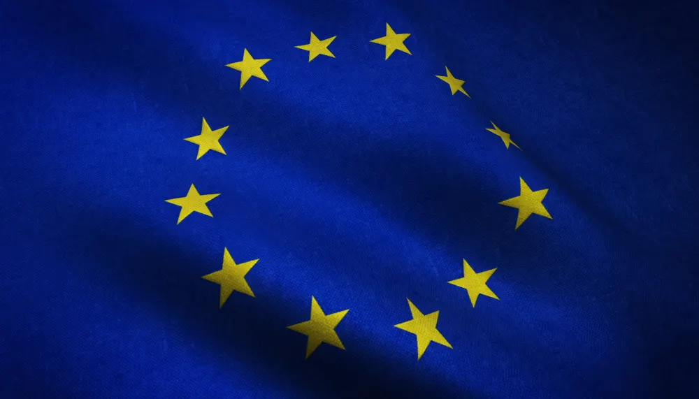 Bandeira da União Europeia ondulando, com doze estrelas amarelas em círculo sobre fundo azul.