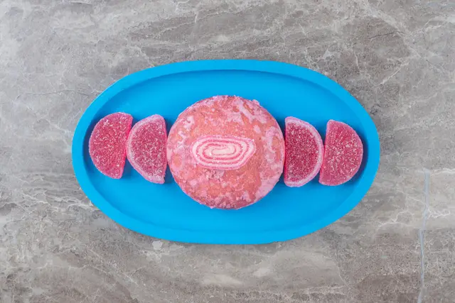 Porções de carne cultivada de cor rosada em uma bandeja azul sobre uma superfície de mármore cinza