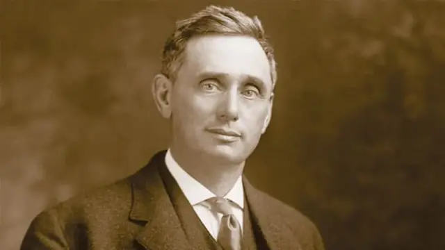 Retrato em sépia de um homem de cabelo curto com terno escuro, camisa branca e gravata, imagem do juiz Louis Brandeis